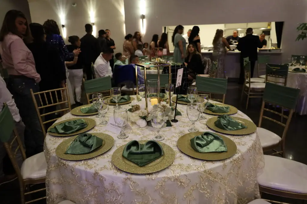 Recepción nupcial, lugar para celebrar la boda, bar completo, comodidades, novios, combinación de colores verde y dorado, centros de mesa altos, flores blancas y crema, servicio de cena tipo buffet desde la cocina