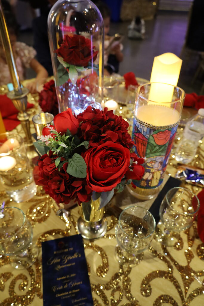 Stunning 'Beauty and the Beast' Quinceañera table setup featuring a red rose centerpiece under a glass dome, evoking the iconic story