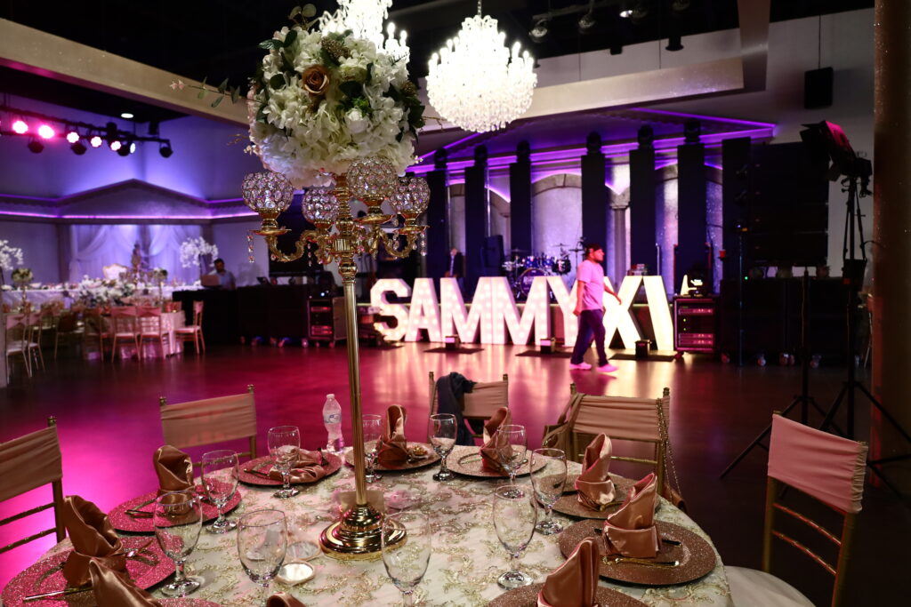 Blush & Gold Quince XV Royal ballroom decorated with elegant drapery, chandelier lighting, and luxurious table settings available for rent