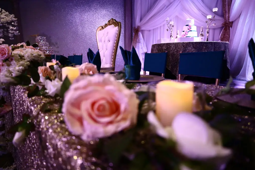 Honoree table at a Quinceañera party in a majestic banquet hall, featuring elegant decorations, floral centerpieces, and luxurious table settings