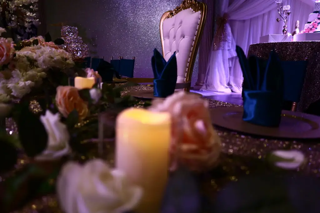 Honoree table at a Quinceañera party in a majestic banquet hall, featuring elegant decorations, floral centerpieces, and luxurious table settings