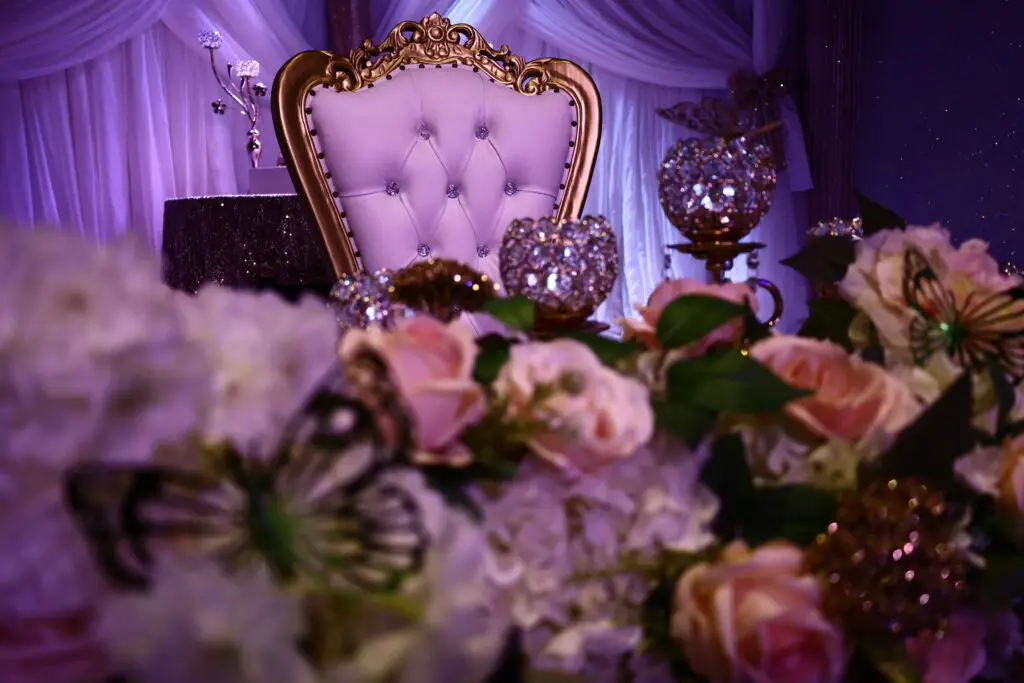 Honoree table at a Quinceañera party in a majestic banquet hall, featuring elegant decorations, floral centerpieces, and luxurious table settings