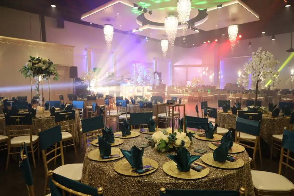 Quinceañera party in a majestic banquet hall with green and gold decor, featuring elegant table settings, vibrant floral arrangements, and sophisticated lighting